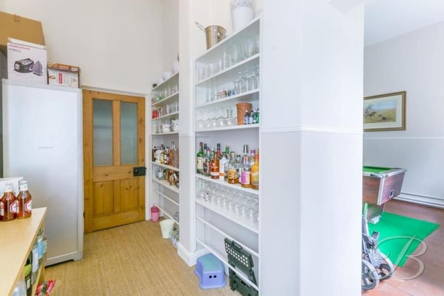 Next door to the pool room is this handy pantry. It has a fitted shelving unit and windows to the side and front of the house.