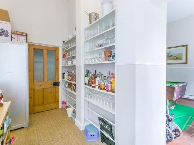 Next door to the pool room is this handy pantry. It has a fitted shelving unit and windows to the side and front of the house.