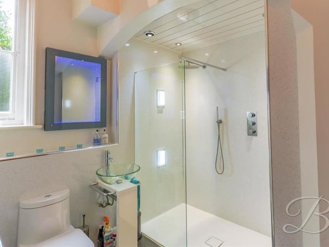 The spacious ground floor at the Mansfield property also features this shower room. It comes complete with a walk-in shower cubicle, low-flush WC, glass hand wash basin, chrome, heated towel-rail, infinity mirror, storage cupboard and fitted shelves.