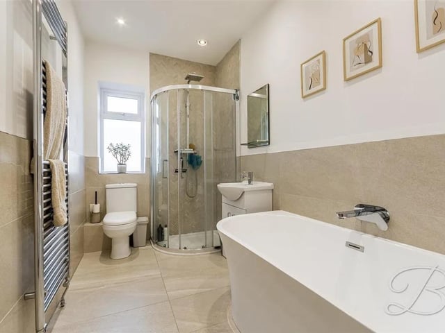 Completed with four piece suite including a low flush WC, hand wash basin, shower cubicle and a large bath set into a matching surround. Finished with tiled flooring, central heating radiator and window to rear elevation.