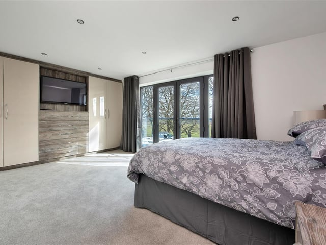 A lovely second bedroom, having a range of contemporary fitted contemporary wardrobes to one wall s and a Juliet balcony to the front elevation with French doors affording wonderful open countryside views.