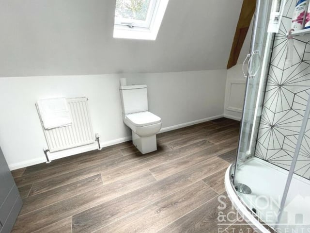 Another of the three en suite bathrooms, attached to the first-floor bedrooms. It boasts a shower cubicle, vanity unit with sink, and low-level WC.