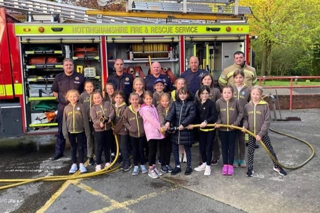 Member of the 2nd Kirkby Brownies with firefighters.