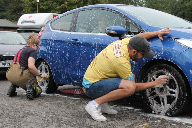 An action shot of firefighters and volunteers cleaning cars as part of the charity car wash.