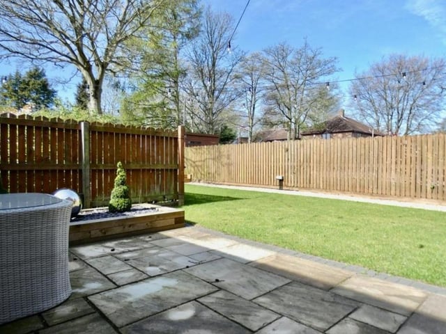 The first of four photos of the back of the Forest Town property. A landscaped, enclosed garden boasts this patio area.