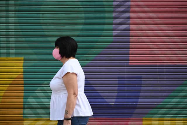 A shopper wearing a face mask walks (Photo by OLI SCARFF/AFP via Getty Images)