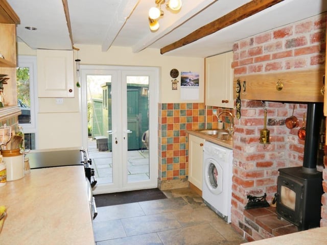 The kitchen ceiling boasts feature beams, while ceramic tiles cover the floor and double-glazed French doors lead out to the rear harden of the property.