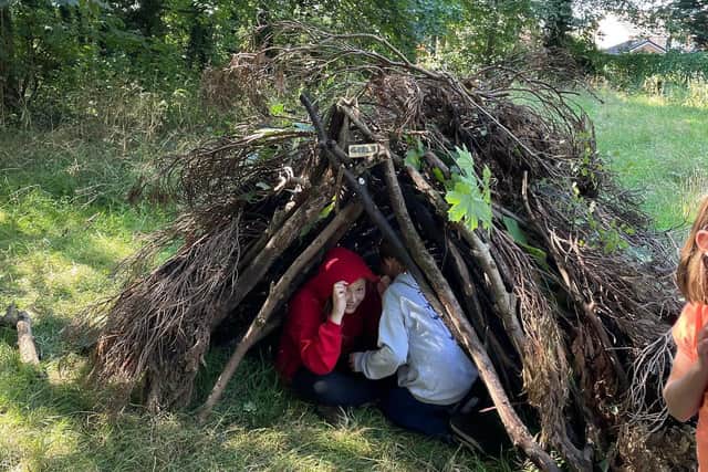 Youngsters hide inside a den they have built using their newly-learned bushcraft skills.