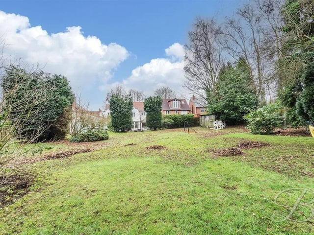 The rear garden unfolds into an expansive, beautifully landscaped space, featuring a generous two-tier patio perfect for alfresco dining and entertaining in style.
