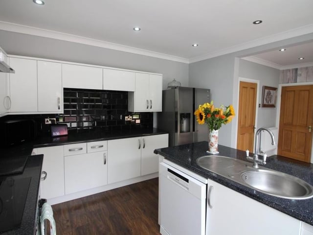 Moving further into the dining kitchen, we can see that a central island is fitted with base units and a stainless steel sink and drainer unit. with integrated dishwasher. Ceiling spotlights give the room a contemporary look.