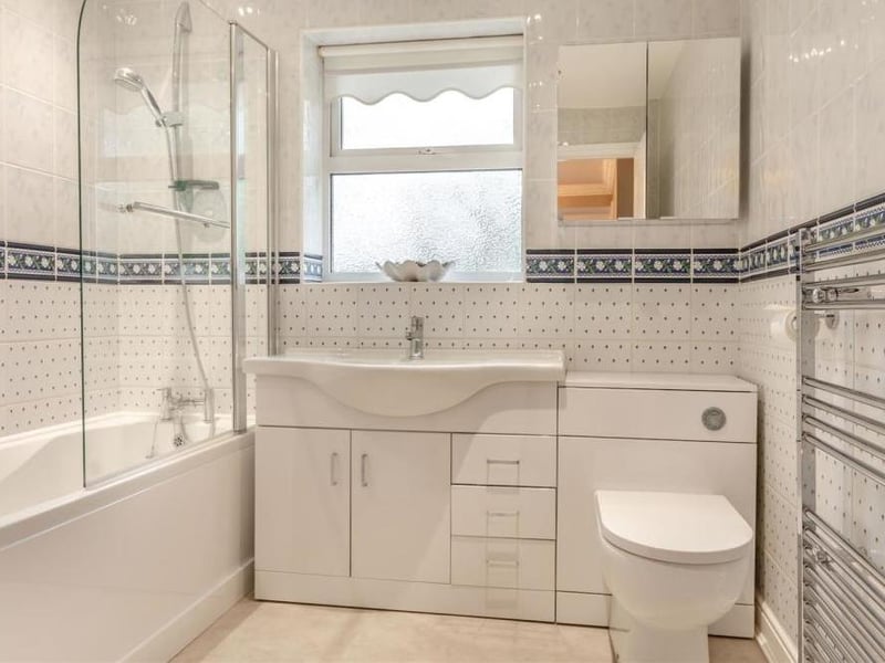 The family bathroom is a modern affair, dominated by a panelled bath with mixer tap and shower over. Close by is a vanity unit with inset wash hand basin, storage cupboard and drawers, plus a low-flush WC. There's also a chrome, heated towel-rail, fully tiled walls, four ceiling spotlights and a tile-effect laminate floor.