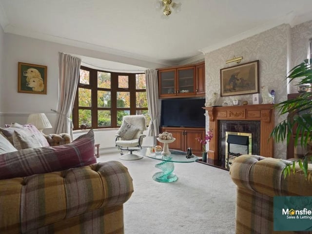 The spacious living room features a charming bay window and a statement fireplace, creating a warm and inviting atmosphere for relaxing evenings.