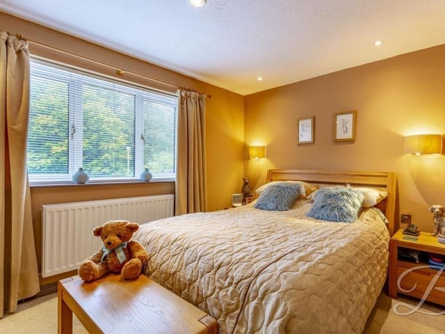 Up to the first floor, where a landing guides us to four of the bedrooms, including this master, which has its own walk-in wardrobe and en suite bathroom, as well as a carpeted floor, downlights and a window facing the front of the house.