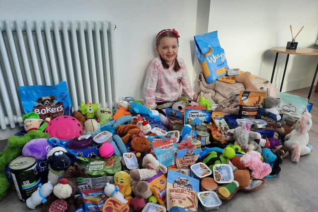 Madeleine Riley, seven, surrounded by the dozens of doggy donations she’s received.