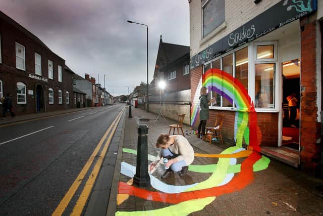 Jayne Woodbridge paints her shop front with a giant rainbow. Picture: Lorne Campbell / Guzelian