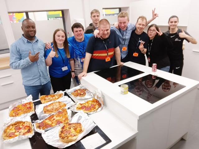 The group with support staff after creating their pizzas