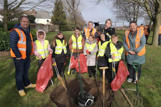 Schoolchildren and douncillors plant the tree.