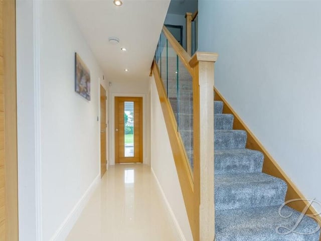 As we prepare to move up to the first floor, let's pass through the entrance hall, which has a tiled floor, downlights and underfloor heating. Under the stairs is a storage cupboard.