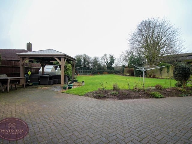 The back garden includes a covered seating area, as well as a block-paved patio, a well-maintained lawn and a timber-built summer house.