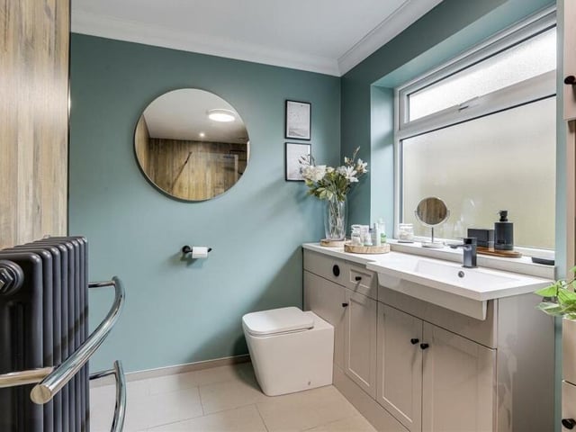 The stylish shower suite also boasts a vanity unit wash basin with fitted storage, a concealed-flush WC, a chrome towel-rail and panelled feature splashback.