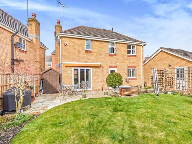 Let's take a step outside now, and here is the delightful back garden. It features a lawn, a multitude of well-established plants and shrubs, plus a paved patio area for seating.