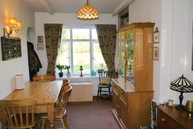 The delightful dining room is at the back of the cottage and offers open views of the countryside. Stairs lead down to the kitchen, which can be found in the basement.
