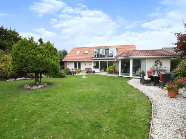 Time to step outside, and this is the property as it looks from the rear. A beautifully landscaped garden is predominantly lawned, with one or two lovely trees. Look closely and you can spot the balcony to the master bedroom.
