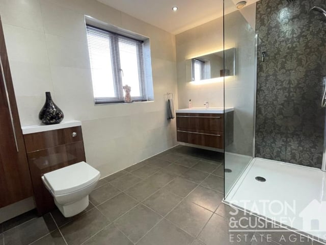 This family shower room can also be found on the first floor. It is fitted with a walk-in shower cubicle, floating drawers with a top-mounted sink and mixer tap, low-level WC and vanity unit, tiled floor, spotlights and a heated towel-rail.
