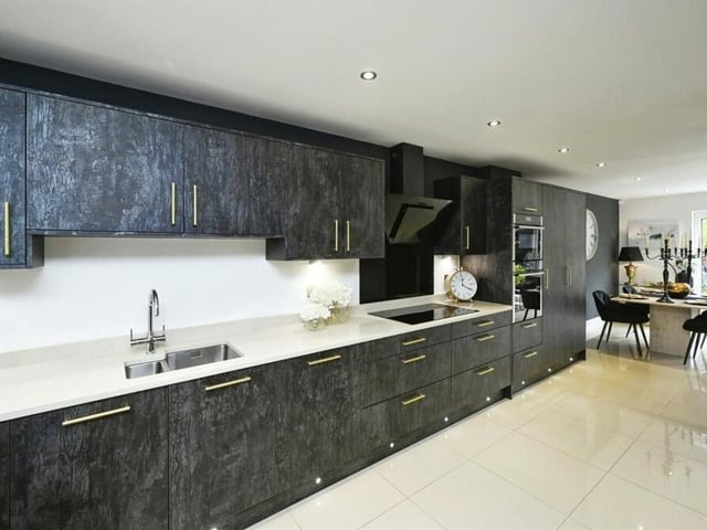 Here is the contemporary kitchen, complete with a stylish range of base and wall-mounted units, extra larder storage units, work surfaces and an inset stainless steel sink with a Quooker tap. Integrated appliances include a five-ring induction hob with a designer cooker hood above.