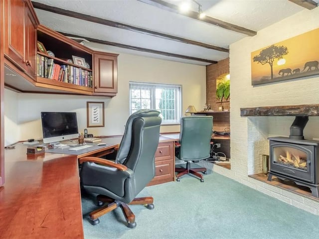 A fantastic home office room, having a brick fireplace with inset log effect gas fire and quarry tiled hearth. Recessed areas to both sides of the fireplace with further brick features and shelving. This room has fully fitted office furniture featuring a substantial L-shaped desk with ample drawer units and storage cupboards. Beamed ceiling, radiator and two double glazed windows to the front elevation.
