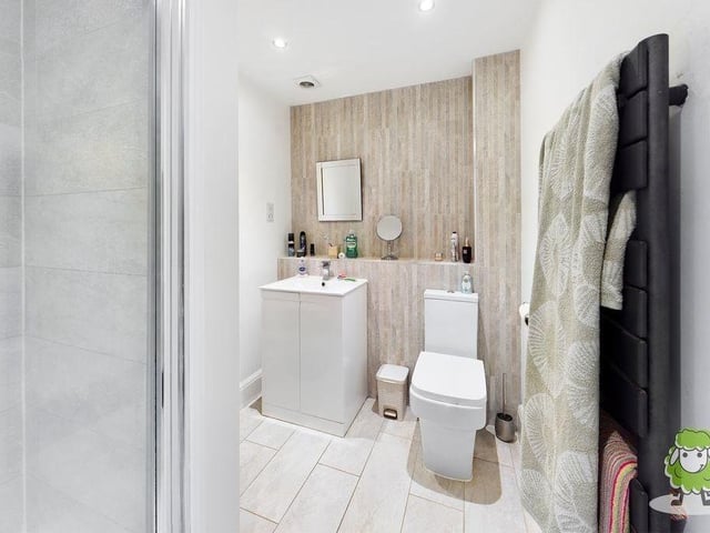 The en suite to the master bedroom is attractive, with its large shower, light tiles and white units.