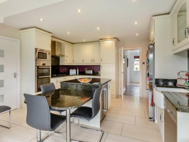Integrated appliances within the kitchen include a single oven, separate oven/grill and microwave and five-ring gas hob, plus plumbing for a dishwasher and space for a fridge freezer. A range of contemporary cabinets, cupboards, base units and drawers are complemented by black granite worktops, plus an inset Belfast ceramic sink with chrome Quooker tap.
