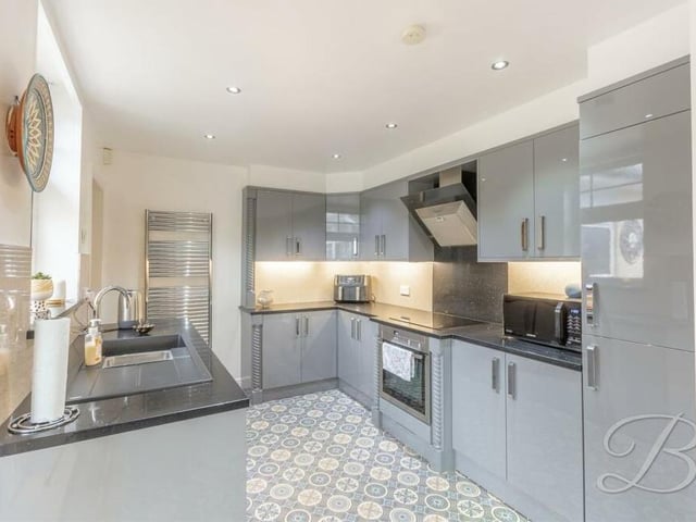 The kitchen is distinguished by a range of modern gloss units and cabinets, work surfaces over and an inset resin sink with drainer. Not even Gordon Ramsay would complain!
