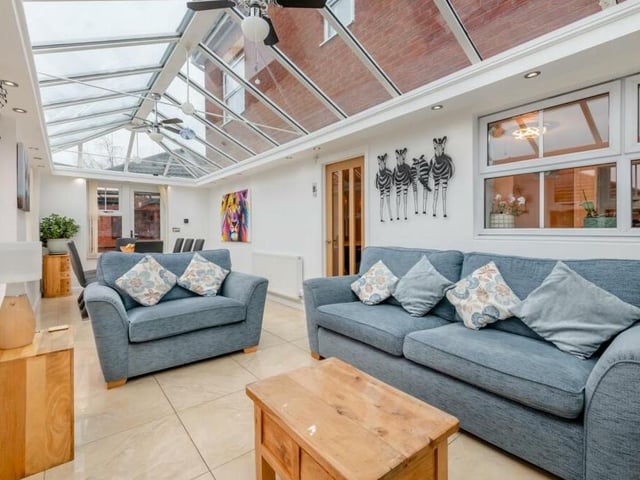 Underfloor heating and an atrium-style, double-glazed roof add style to the conservatory, which also has ceiling spotlights and a polished ceramic-tiled floor. The door to the right leads into the kitchen.