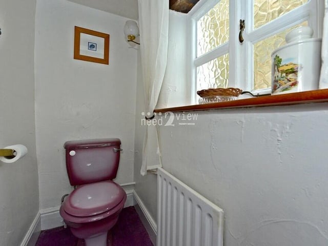The last room to check out on the ground floor is this downstairs toilet. Separate to the bathroom, it features a purple WC, an opaque window facing the rear of the cottage and more ceiling beams.