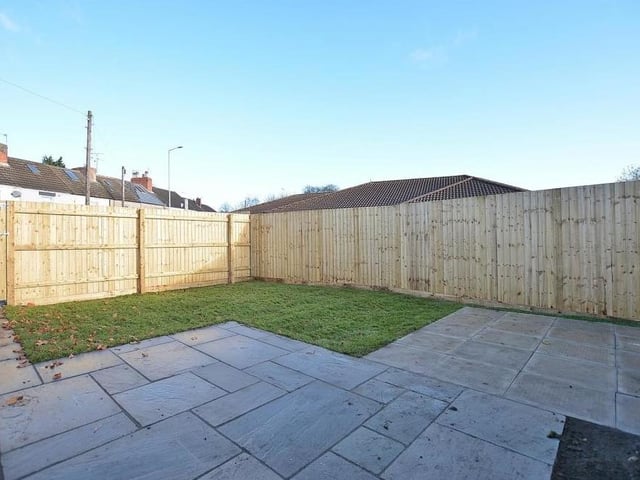 Let's see what the exterior has to offer at Kings Court. This is the garden at the side, featuring a lawn and an Indian sandstone patio and path. It is fully enclosed, offering a good degree of privacy.