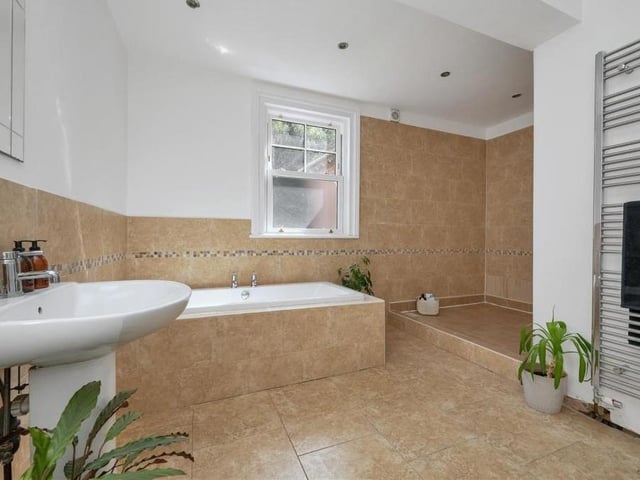 Also on the first floor of the six-bedroom Mansfield house is this family bathroom. A four-piece suite with chrome fittings consists of a tiled, inset bathtub, substantial walk-in tiled shower area, pedestal wash hand basin with mixer tap and low-flush WC. A tiled floor, seven ceiling spotlights and a chrome, heated towel-rail add extra lustre.