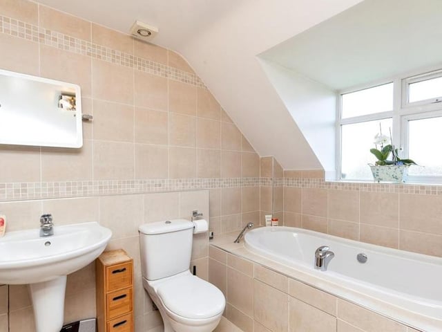Completing our tour of the interior is this family bathroom. It is fitted with a bath that has an extendable shower head, a wash hand basin, WC, tiled walls and splashbacks, tiled flooring, an extractor fan and a towel radiator.