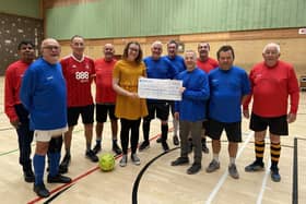 Members of Hucknall Walking Football team present the cheque to Holly Younger, daughter of Leon Smith