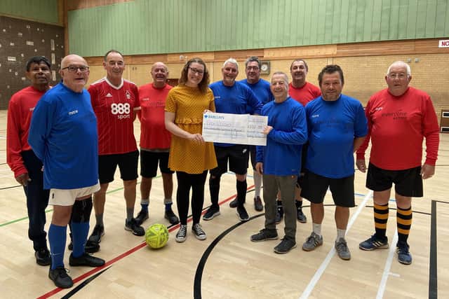 Members of Hucknall Walking Football team present the cheque to Holly Younger, daughter of Leon Smith