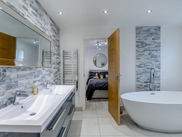 This excellently appointed Jack and Jill bathroom serves as an en suite facility for the third and fourth bedrooms. A large, oval-shaped Moda bath-tub is a striking feature, but there is also a double vanity unit with his and hers sinks, storage drawers, a wall-hung, low-flush WC, chrome, heated towel-rail, porcelain-tiled floor, nine LED ceiling spotlights and feature quartz tiling.