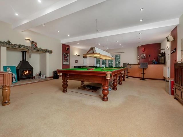 The games room even features an attractive inglenook fireplace with inset log burner, mounted on a sandstone hearth. At the far end is the bar.