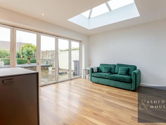 The kitchen opens onto a light filled living room with patio doors and skylight windows.