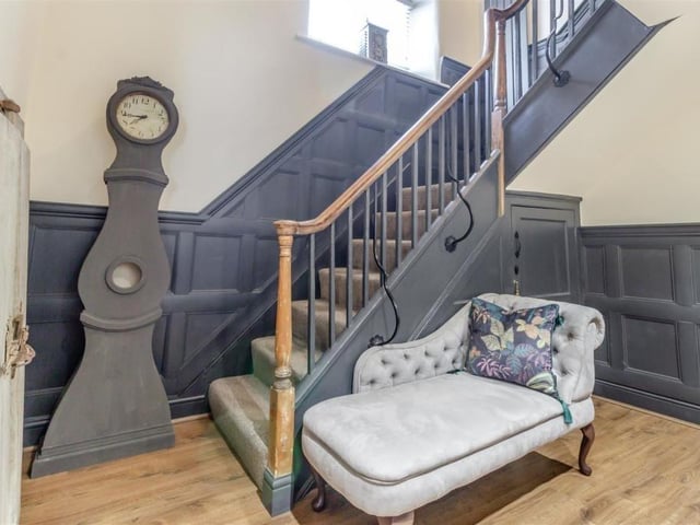 The hallway is a stunning space within the restored building. It features the original Victorian staircase handrail, complemented by panelled walls painted in satin grey. The full-height ceiling opens to the galleried landing upstairs, while the floor is solid oak and there is a storage cupboard under the stairs.