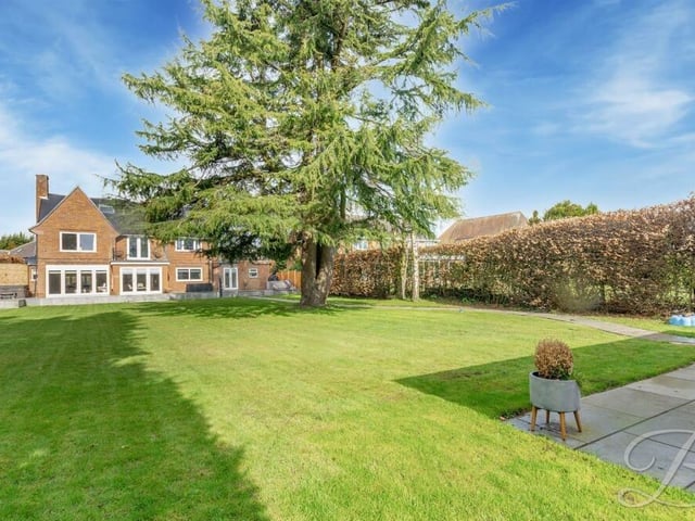 The lawn at the back of the house is extensive and well maintained. Mature trees add to the garden's appearance.
