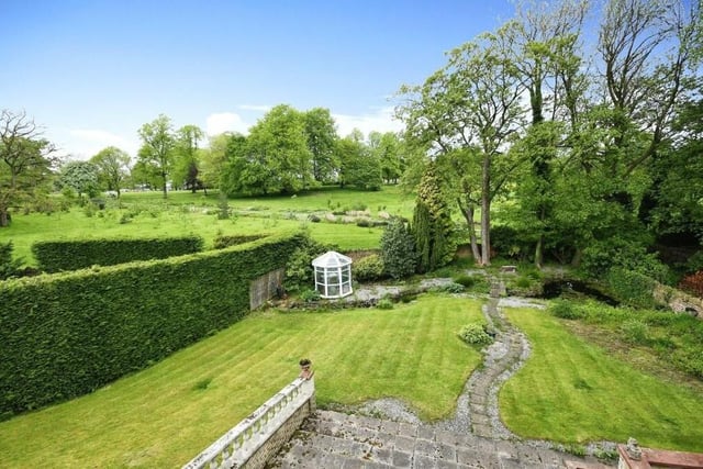 An overview of the well-maintained back garden, with its extensive lawn, pond and wide range of borders, shrubs and trees.