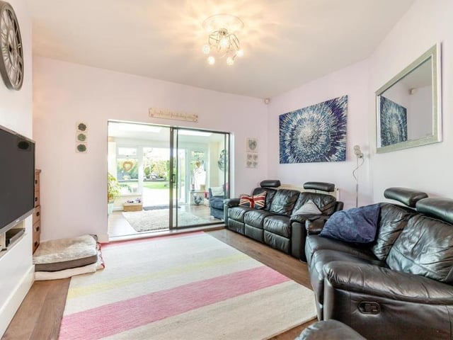 Here is the open-plan lounge, which offers comfort and brightness. There is a log burner with a slate hearth, while a sliding patio door leads into the garden room.
