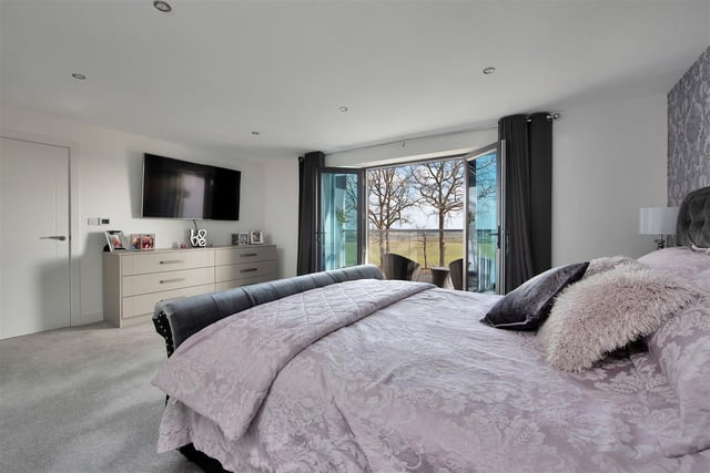 A large master bedroom with dressing room and en suite and French doors leading out onto a balcony.