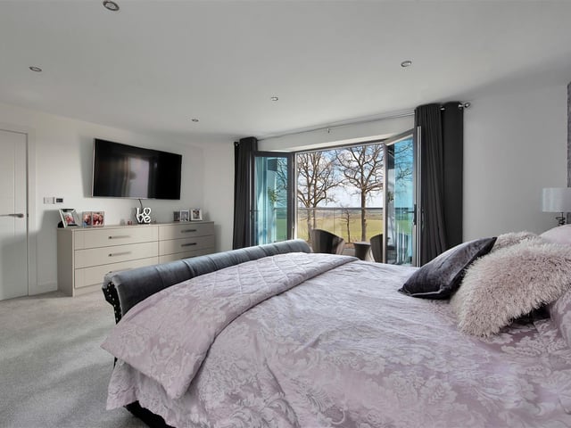 A large master bedroom with dressing room and en suite and French doors leading out onto a balcony.