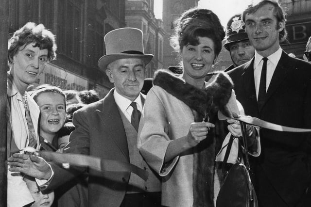 Actress Pat Phoenix, also known as Elsie Tanner of Coronation Street, cuts the tape to officially open Top Clothing Store in King Street.  With her is actor Roger Adamson, who also appeared in Coronation Street. This one takes us back to 1964.